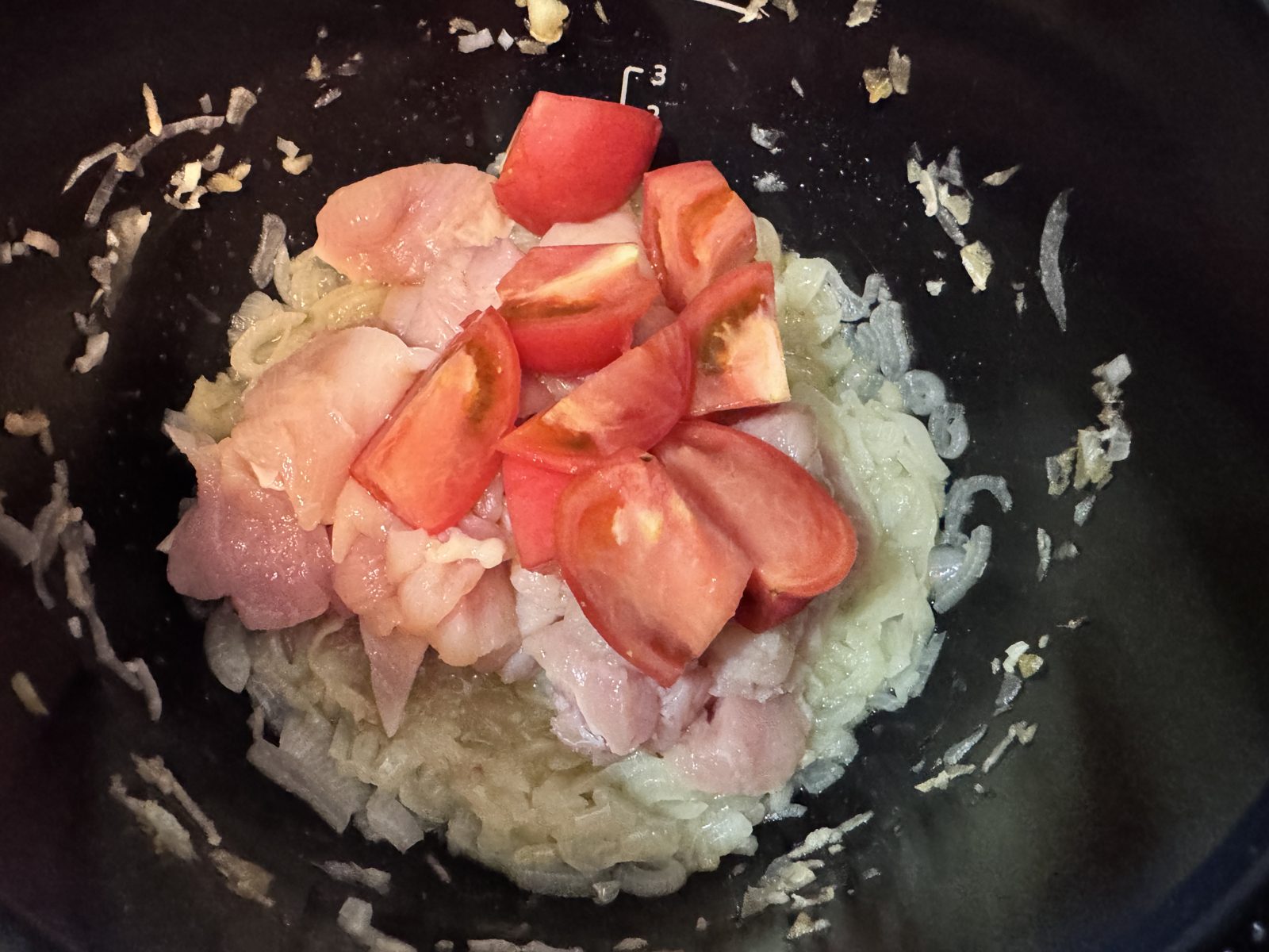 炒めた玉ねぎの上に鶏むね肉と生トマトをのせたところ