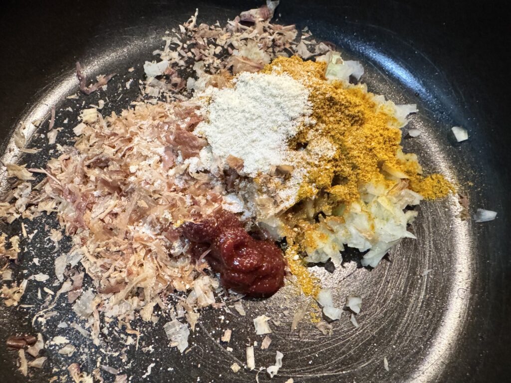 玉ねぎ、花かつお、カレー粉、鶏がらスープ、ケチャップをフライパンに入れたところ(このあとレンジ用の容器に移した)